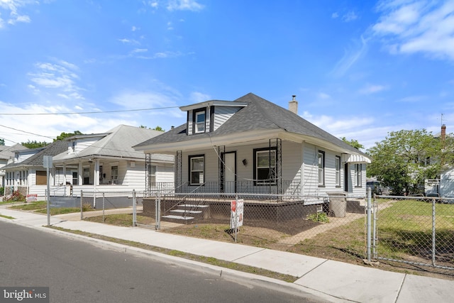 311 W Washington St, Paulsboro, NJ 08066 - view of front facade featuring covered porch, a fenced front yard, a chimney, roof with shingles, and a gate