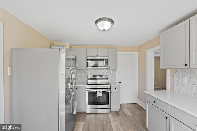 311 W Washington St, Paulsboro, NJ 08066 - kitchen featuring stainless steel appliances, backsplash, light wood-style floors, and light stone counters