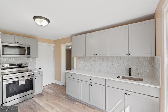 311 W Washington St, Paulsboro, NJ 08066 - kitchen with appliances with stainless steel finishes, a sink, tasteful backsplash, light wood-style flooring, and gray cabinetry