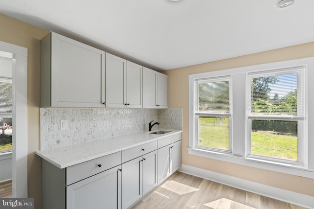 311 W Washington St, Paulsboro, NJ 08066 - kitchen featuring light wood-style flooring, a sink, decorative backsplash, and light stone countertops