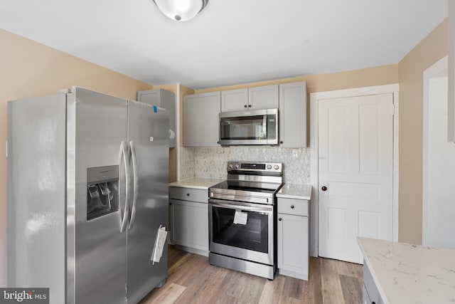 311 W Washington St, Paulsboro, NJ 08066 - kitchen featuring appliances with stainless steel finishes, gray cabinets, tasteful backsplash, and light wood-style flooring