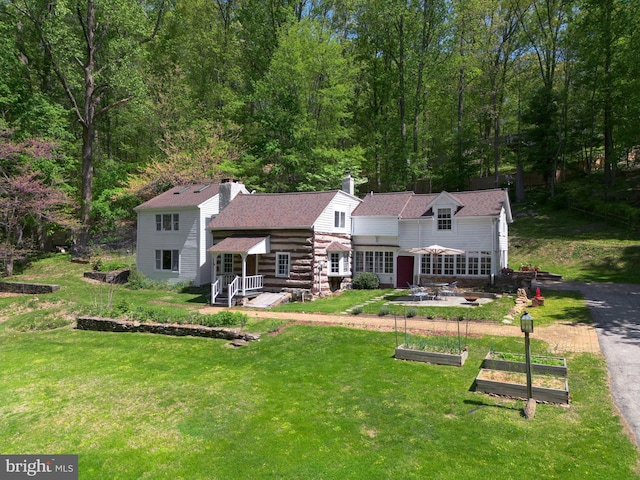 1180 Radnor Hill Rd, Wayne, PA 19087 - rear view of property featuring a vegetable garden, a yard, a chimney, and roof with shingles