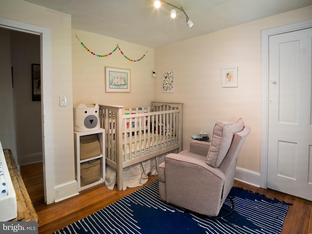 1180 Radnor Hill Rd, Wayne, PA 19087 - bedroom with wood finished floors, baseboards, track lighting, and a nursery area