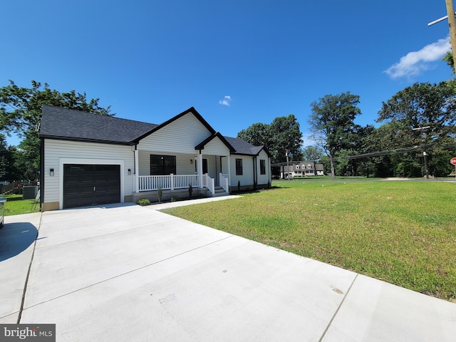 view of front facade with a porch, a garage, concrete driveway, a front yard, and central AC unit