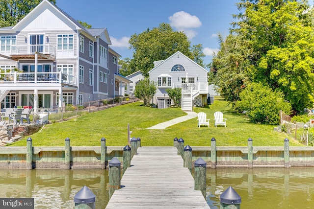 dock area featuring stairway, a lawn, a deck with water view, and a balcony