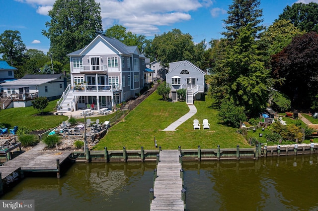 rear view of house with stairway, a yard, a balcony, a deck with water view, and view of scattered trees