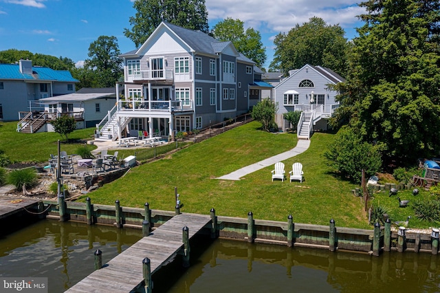 rear view of house featuring stairs, a deck with water view, and a yard