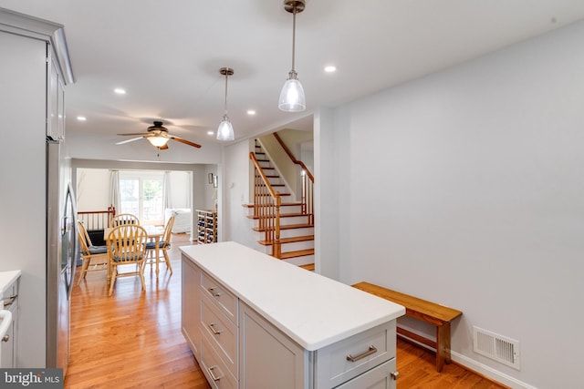kitchen with light wood-style floors, recessed lighting, a kitchen island, light countertops, and hanging light fixtures
