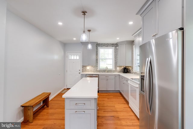 kitchen featuring stainless steel appliances, gray cabinets, backsplash, a sink, and recessed lighting