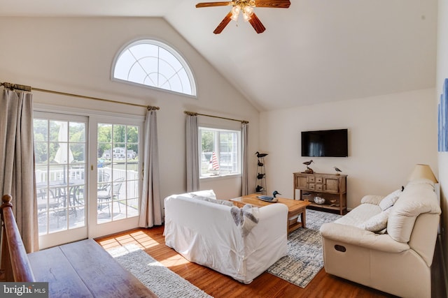 living area with a ceiling fan, wood finished floors, and high vaulted ceiling