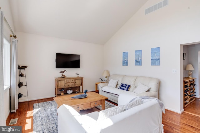 living area with wood finished floors, baseboards, and high vaulted ceiling