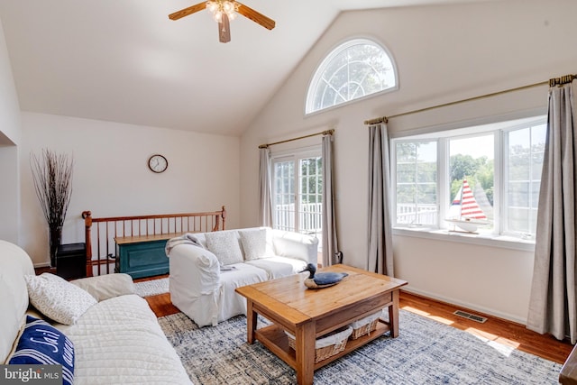 living area featuring ceiling fan, light wood-type flooring, baseboards, and high vaulted ceiling