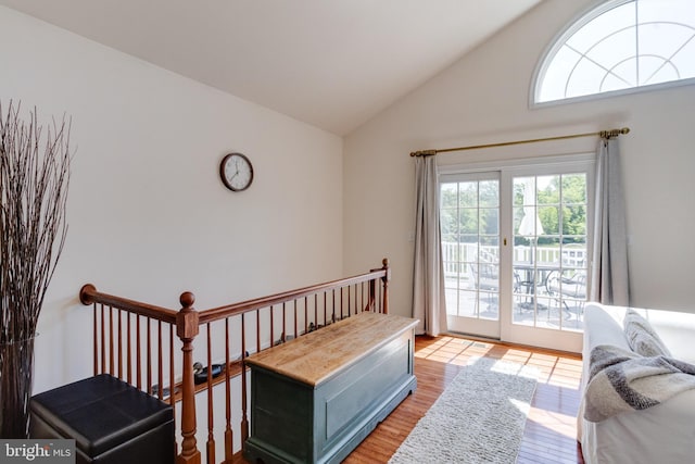 bedroom featuring access to exterior, light wood-style flooring, and high vaulted ceiling