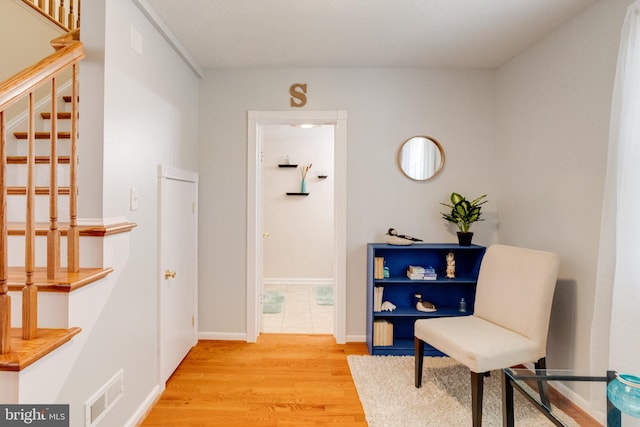 living area with light wood-style flooring, stairs, and baseboards