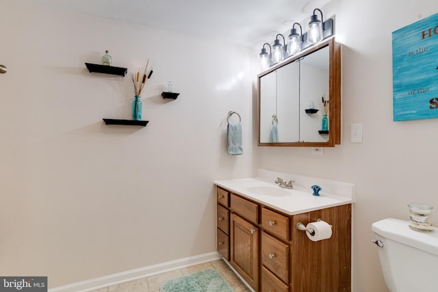 bathroom with vanity, toilet, tile patterned flooring, and baseboards