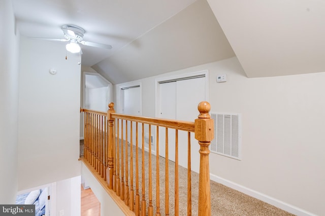 hallway featuring lofted ceiling, an upstairs landing, carpet, and baseboards