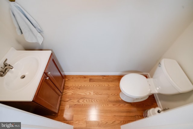 bathroom with wood finished floors, baseboards, toilet, and vanity