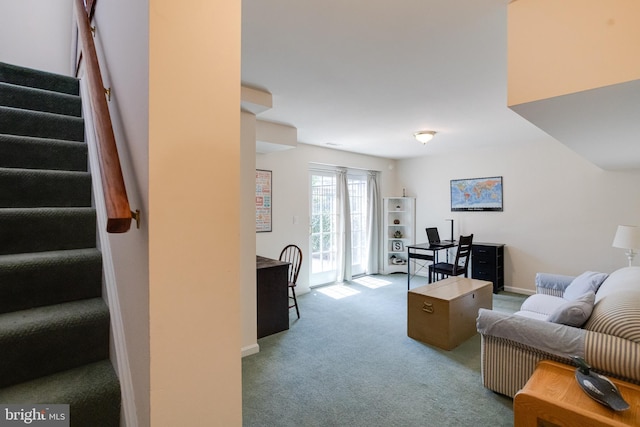 carpeted living area with stairway and baseboards