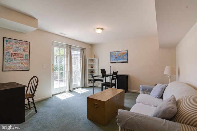 carpeted living room featuring baseboards and a desk