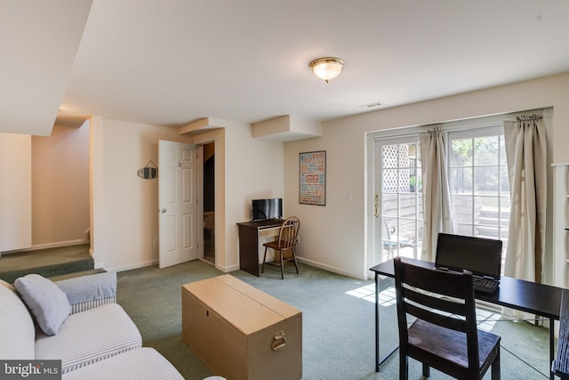 carpeted living area with a desk and baseboards