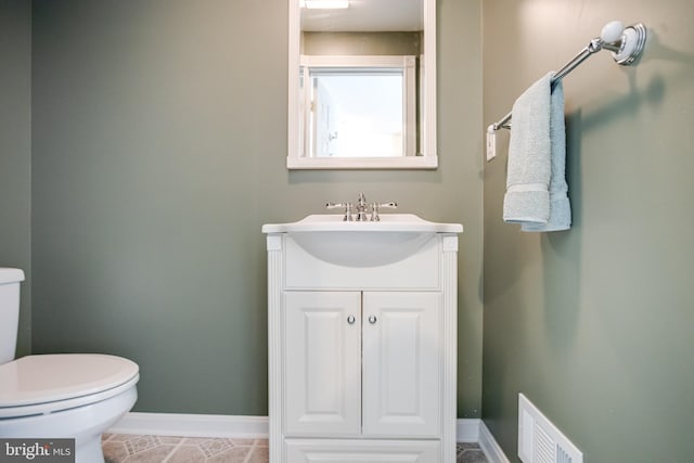 bathroom featuring baseboards, toilet, and vanity