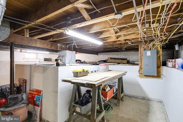 unfinished below grade area featuring electric panel and a workshop area