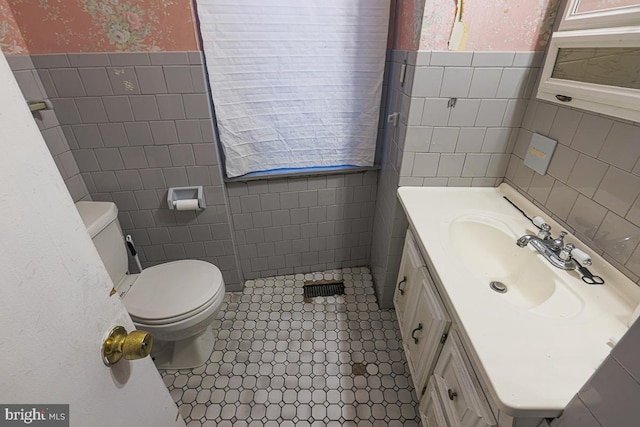 1721 Ruxton Ave, Baltimore, MD 21216 - bathroom with tile walls, toilet, vanity, wainscoting, and wallpapered walls