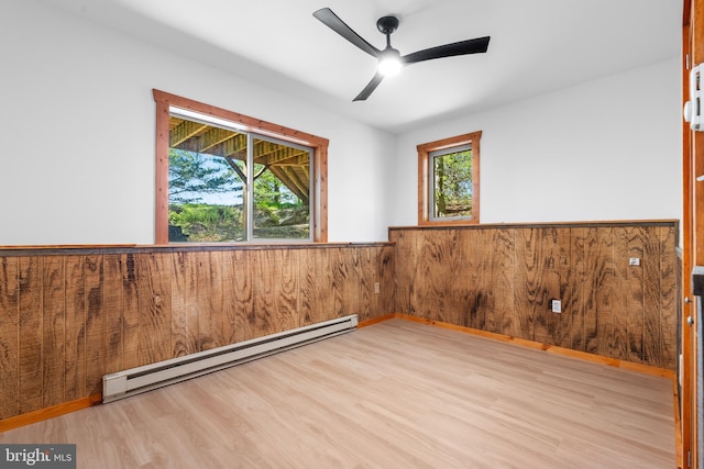 2107 Lenape Ter, Canadensis, PA 18325 - spare room featuring a baseboard radiator, wainscoting, wood finished floors, a ceiling fan, and wooden walls