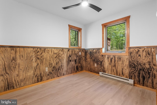 2107 Lenape Ter, Canadensis, PA 18325 - empty room featuring baseboard heating, wainscoting, wood finished floors, a ceiling fan, and plenty of natural light
