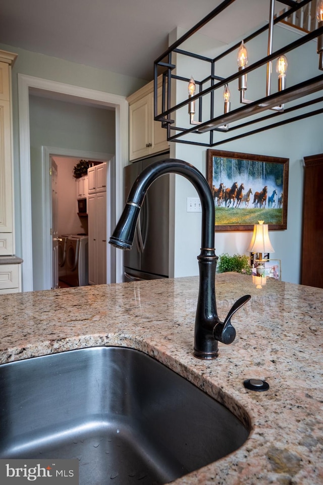 318 Ironstone Ln, Elverson, PA 19520 - kitchen view of cream cabinets, a sink, washer and dryer, and light stone countertops