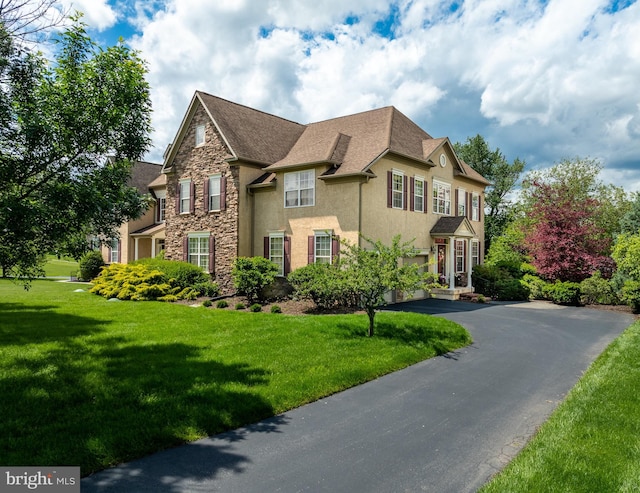 318 Ironstone Ln, Elverson, PA 19520 - view of front of house featuring stucco siding, stone siding, a front lawn, and driveway