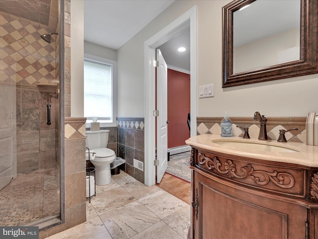 full bath featuring tile walls, wainscoting, toilet, a stall shower, and vanity