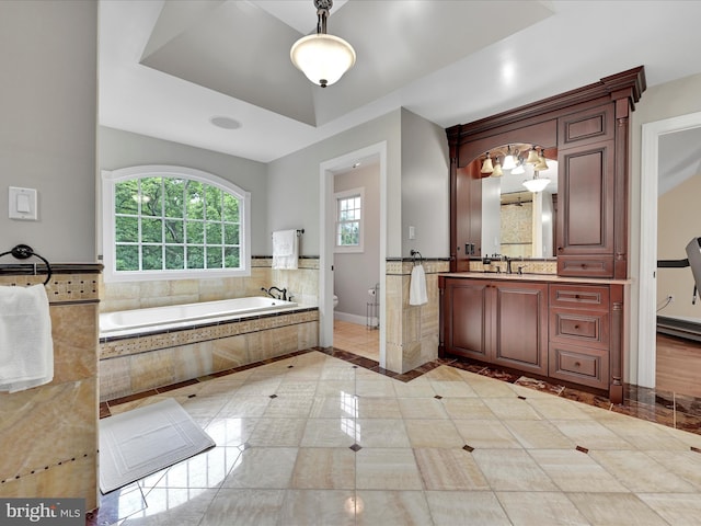 bathroom with toilet, a garden tub, vanity, and baseboards