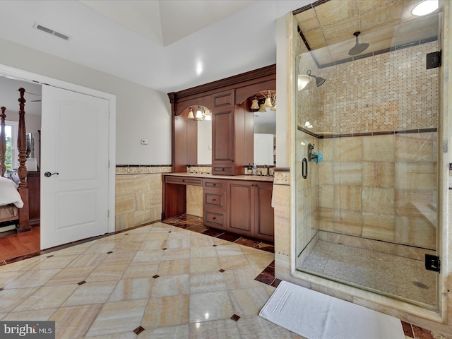 ensuite bathroom with a wainscoted wall, a shower stall, and vanity