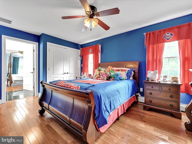 bedroom featuring multiple windows, wood-type flooring, a closet, and baseboard heating