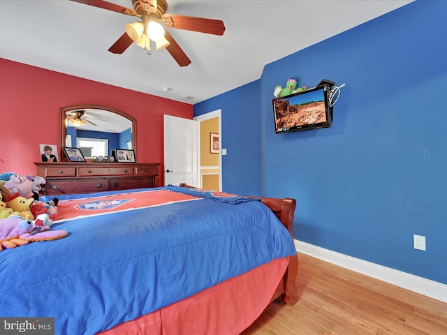 bedroom with light wood finished floors, baseboards, and a ceiling fan