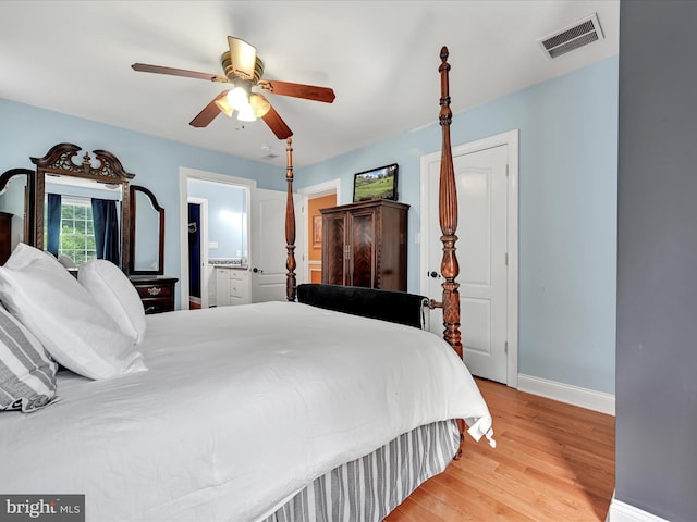 bedroom featuring baseboards, light wood-style flooring, ceiling fan, and connected bathroom