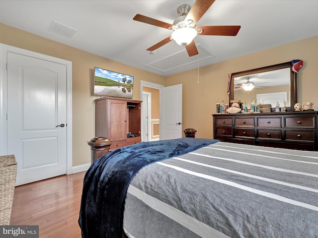 bedroom featuring attic access, light wood finished floors, baseboards, and ceiling fan
