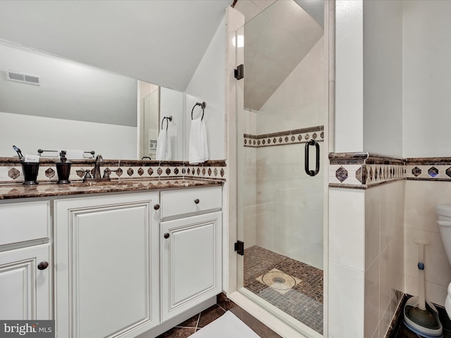 full bathroom featuring a shower stall, toilet, vanity, vaulted ceiling, and tile patterned flooring