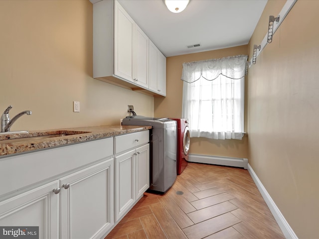 laundry area featuring baseboard heating, independent washer and dryer, cabinet space, and baseboards