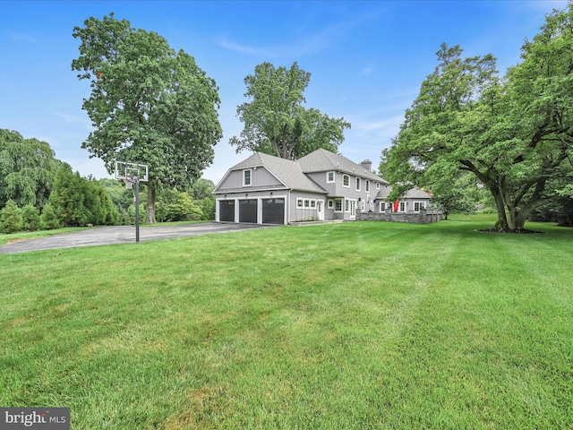 view of front of property featuring driveway, a front lawn, a chimney, an attached garage, and a shingled roof