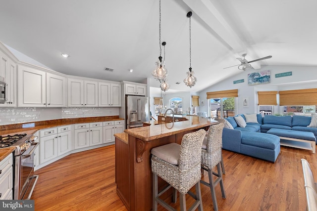 38 N 10th St, Surf City, NJ 08008 - kitchen with stainless steel appliances, ceiling fan, open floor plan, a breakfast bar, and light wood finished floors