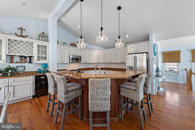38 N 10th St, Surf City, NJ 08008 - kitchen with stainless steel appliances, dark stone countertops, a breakfast bar, glass insert cabinets, and wood finished floors