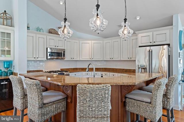38 N 10th St, Surf City, NJ 08008 - kitchen with stainless steel appliances, vaulted ceiling, light wood-style floors, decorative backsplash, and a kitchen breakfast bar