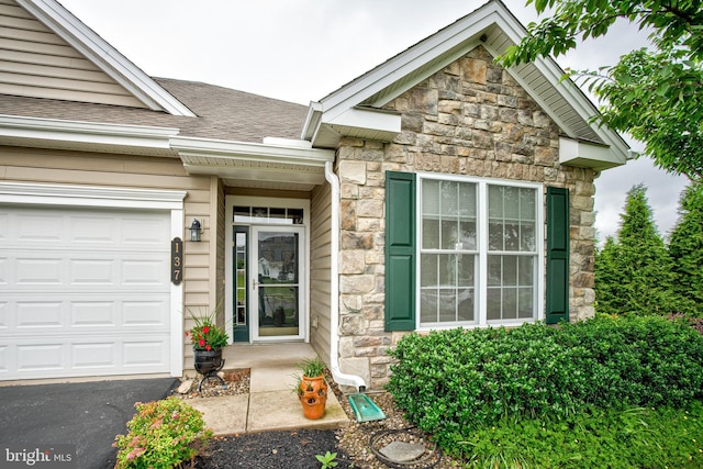 137 Settlers Way, Boalsburg, PA 16827 - view of exterior entry with stone siding, roof with shingles, an attached garage, and driveway