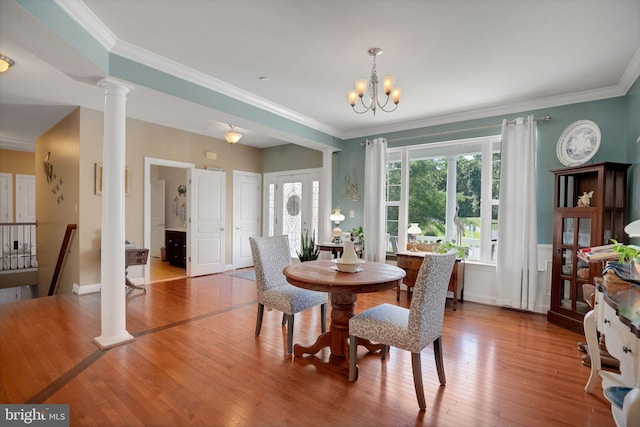 26248 Tranquility View Ct, Mechanicsville, MD 20659 - dining room with ornate columns, crown molding, hardwood / wood-style floors, a chandelier, and wainscoting