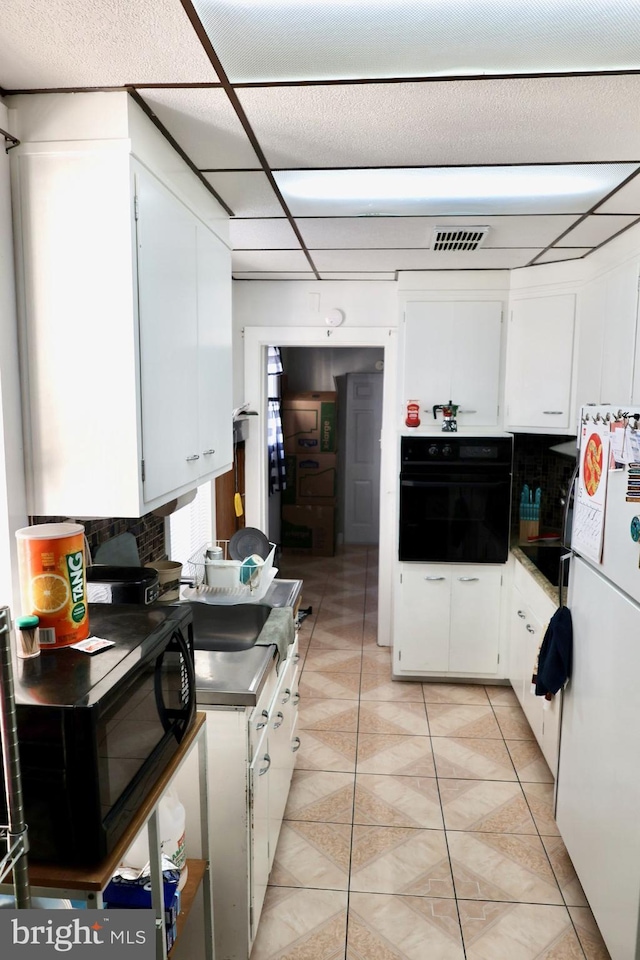 952 Moss St, Reading, PA 19604 - kitchen with black appliances, white cabinetry, and light tile patterned floors