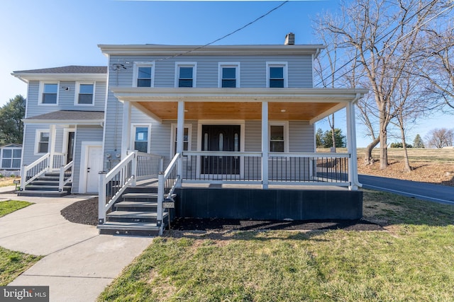 view of front of house with covered porch, a front yard, and a chimney
