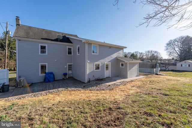 back of property with a patio, a lawn, a cooling unit, and a chimney