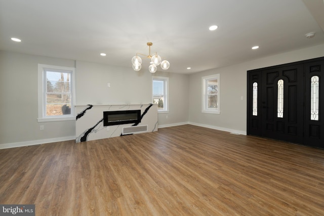 foyer entrance with a high end fireplace, baseboards, wood finished floors, and recessed lighting